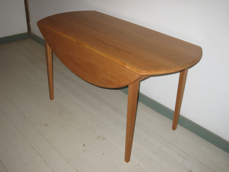 Elliptical drop leaf dining table in cherry. 60" l x 25.5" wide with leaves down